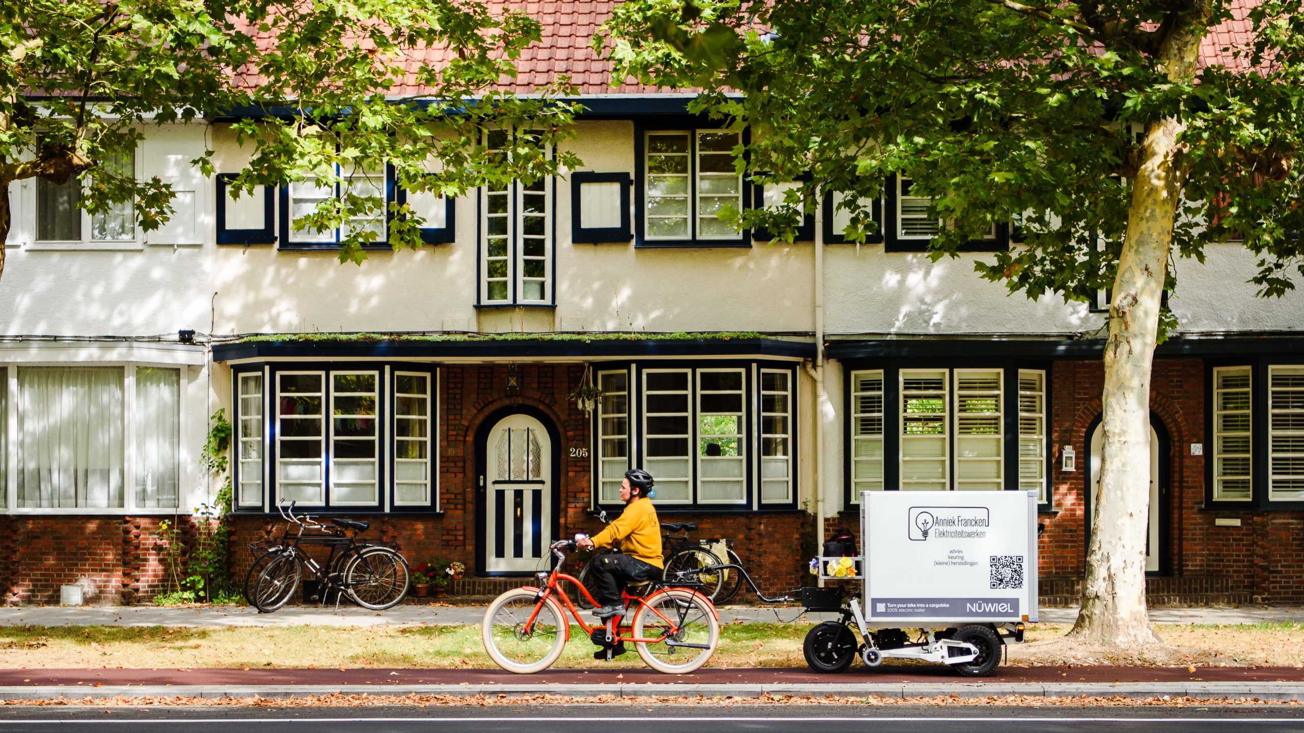Electrician Anniek Francken transporting her professional tools through the streets of Antwerp with a NÜWIEL eTrailer cargo solution attached to her bicycle.