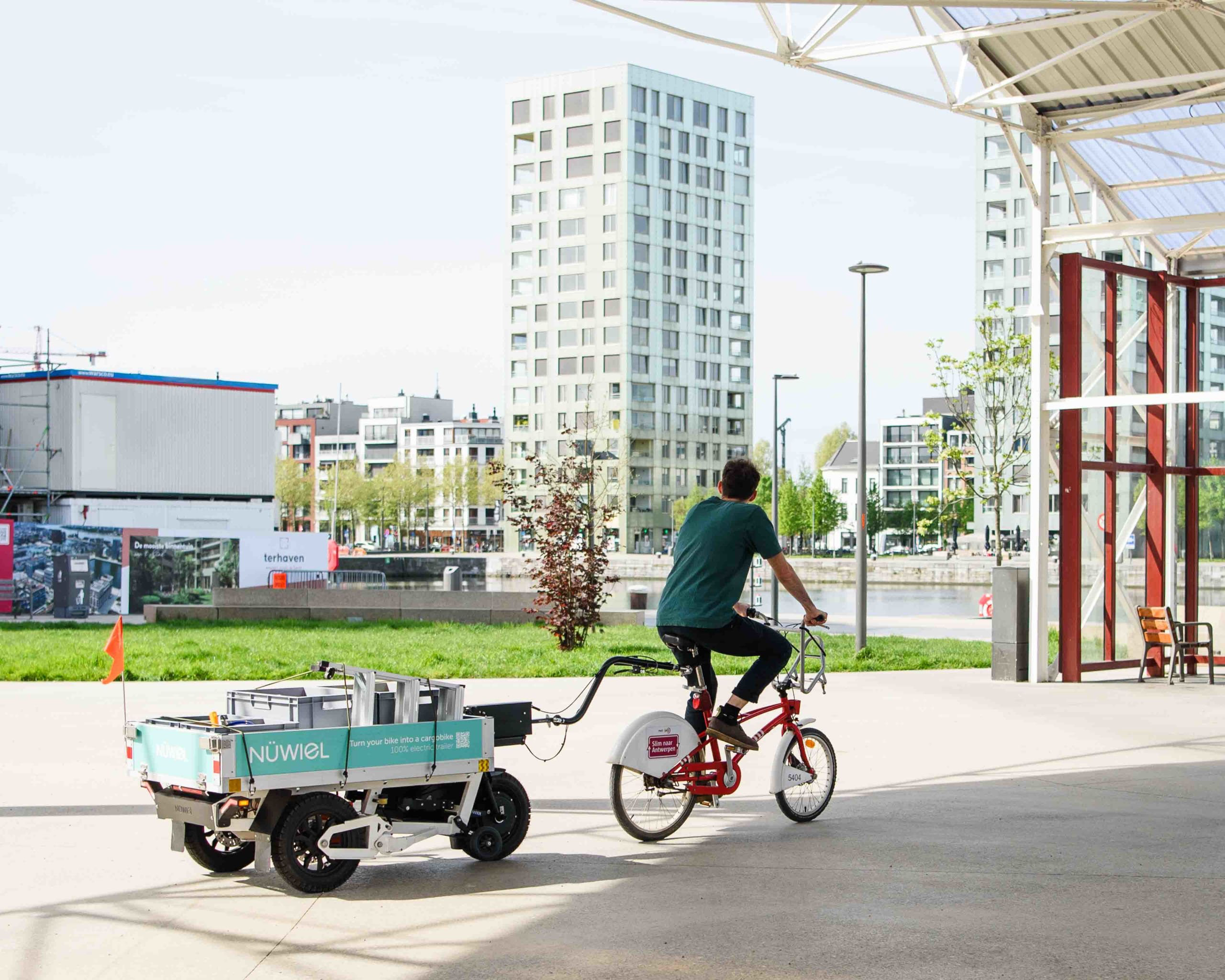 urning a standard bicycle into a high-capacity cargo bike: A NÜWIEL eTrailer in use for urban transport in a modern city district in Antwerp.